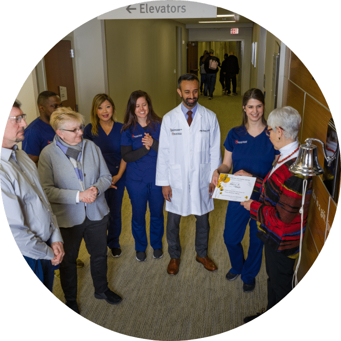 Patient ringing the bell surrounded by her medical team and loved ones