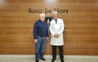 Maryland Proton Treatment Center physician Dr. Zeljko Vujaskovic and patient George Gerakitis posing in front of bell